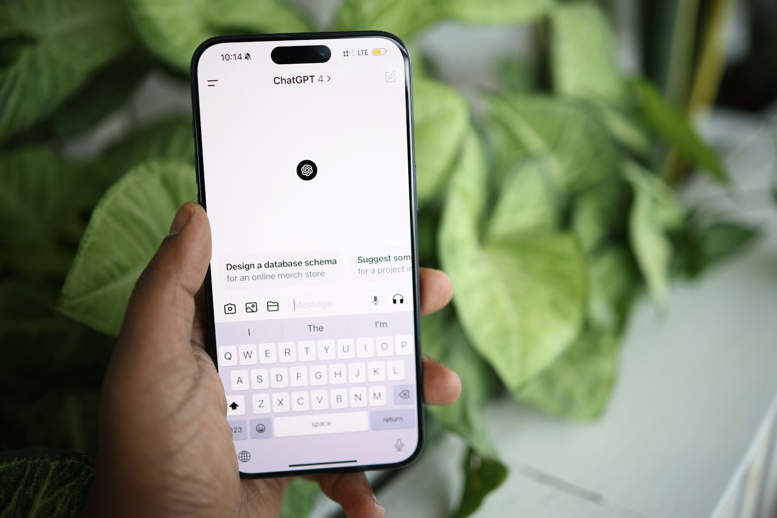 Hand holding a phone with the ChatGPT app open, ready to ask a question